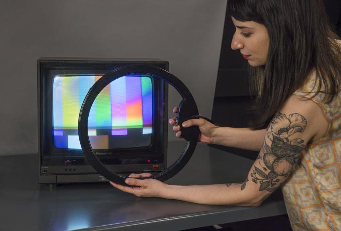 A conservation student uses a deguassing coil, which looks like a large black ring, to calibrate a cathode ray tube monitor.