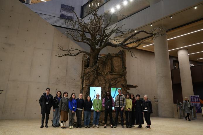 Image of the students with Larry Achiampong and David Blandy in front of their sculpture the Treow of Time